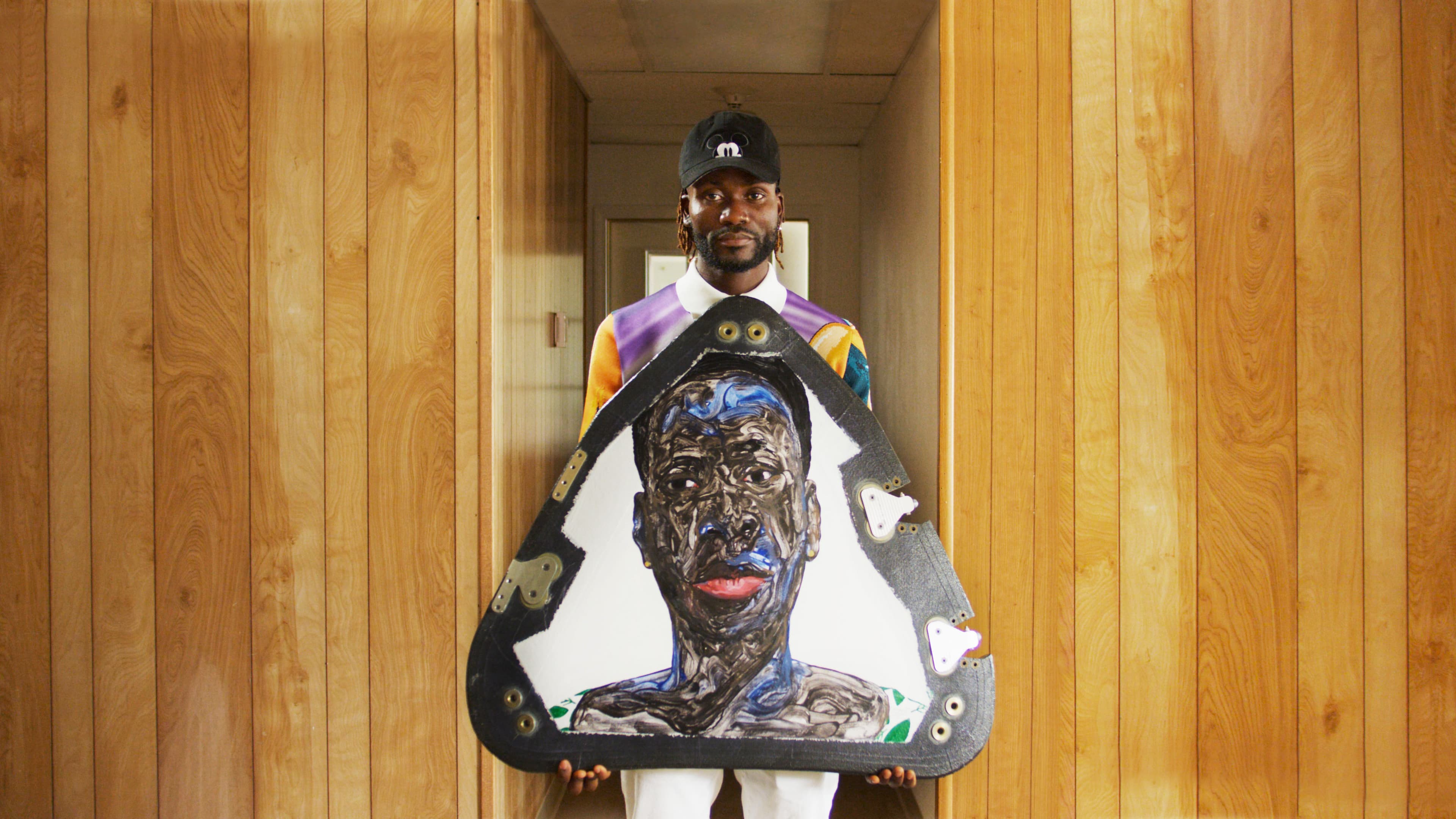 Ghanian artist Amoako Boafo holds a piece of New Shepard’s nose cone, featuring a portrait he painted of a Black man accented with red and blue.