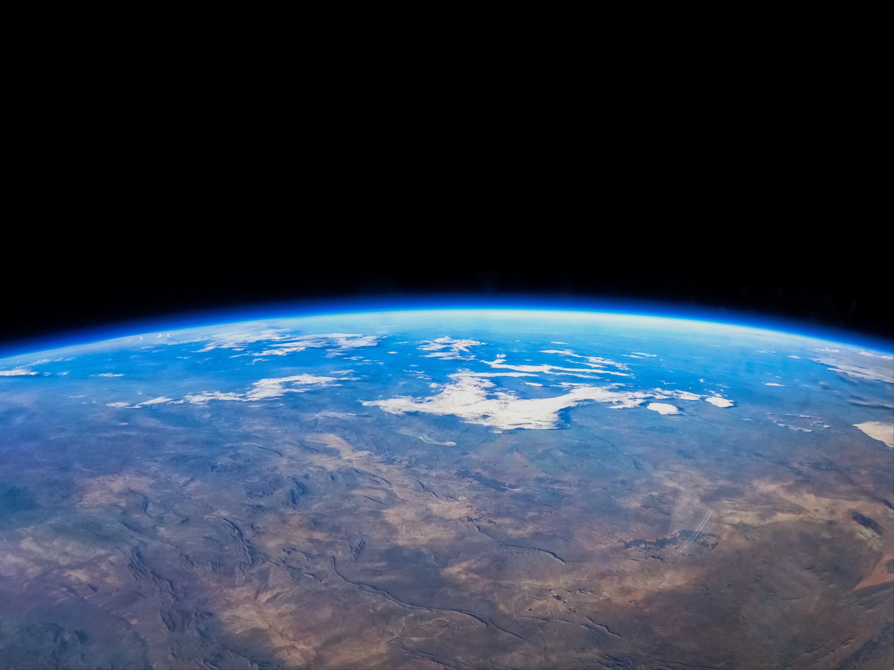 Earth and the thin blue line of its atmosphere as seen from a window inside the crew capsule.
